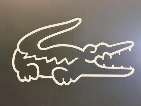 Lacoste logo featuring the iconic white crocodile line art on a dark gray w.. Stockfoto's