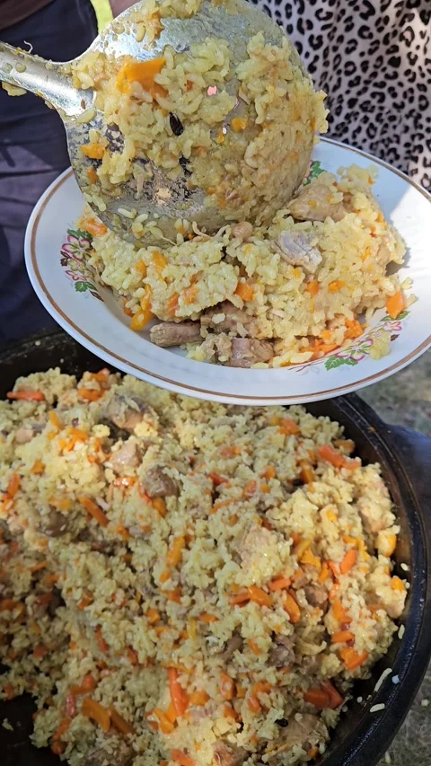A ladle is applied to pilaf from a cauldron. Pilaf is put on a plate Stock Footage 284253405