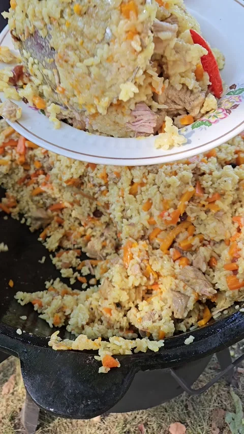 A ladle is applied to pilaf from a cauldron. Pilaf is put on a plate Stock Footage 284253461