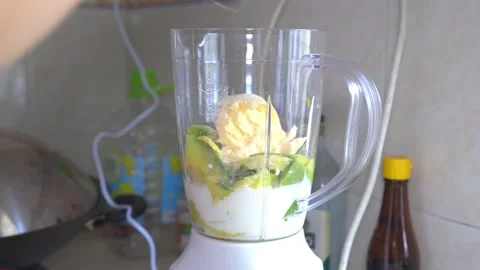 Lady adding avacado fruit and ice cream into brender Stock Footage 254099202