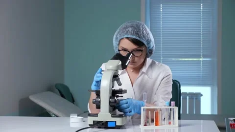 Lady adjusts microscope working with sample in hospital Stock Footage 156700164