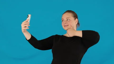 Lady adjusts posture showing thumb up aiming to capture selfie Stock-Footage 316050984