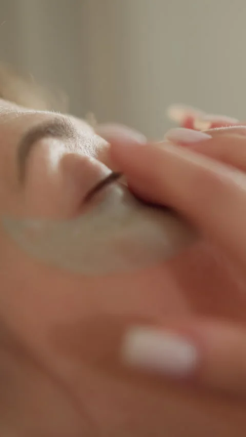 Lady applies moisturizing patch under eyes lying on sofa Vídeos de archivo 309808646
