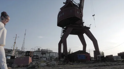 Lady approaches rusty structure against setting sun light Stock Footage 117884945
