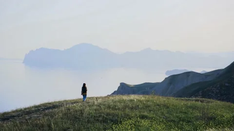 Lady backpacker with black bag walks along green meadow Video stock 157100772