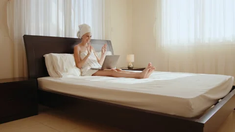 Lady in bath towel using laptop for video call at hotel room Stock Footage 164177194