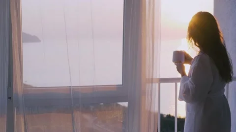 Lady in bathrobe drinks coffee looking at bay from terrace Stock Footage 152407609