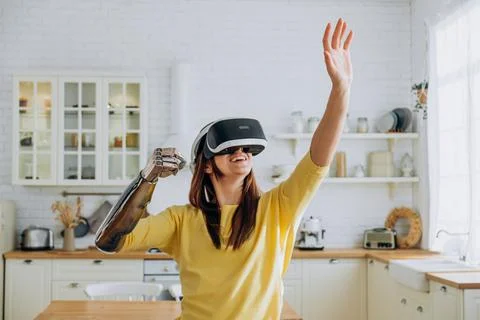 Lady with bionic arm and virtual reality goggles in kitchen Stock Photos