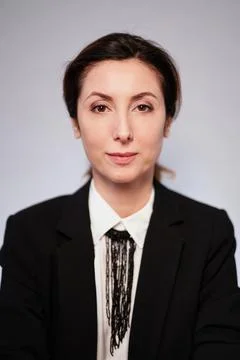 Lady in black jacket posing on grey background looking at camera Stock-Fotos