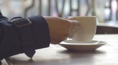 Lady in blue coat drinking coffee against the window Stock Footage 67057218
