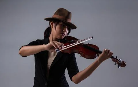 The lady with brown hat is playing violin,put the violin on left shoulder and Stock Photos