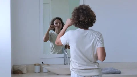 Lady brushes teeth in wireless headphones. Woman listens to music on wireless Stock Footage 257752001