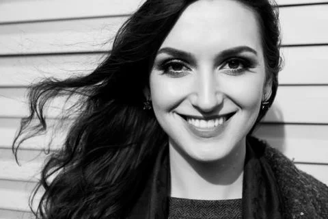 Lady with Charming Smile is Posing on Wall Background. Black and White Urban Photos