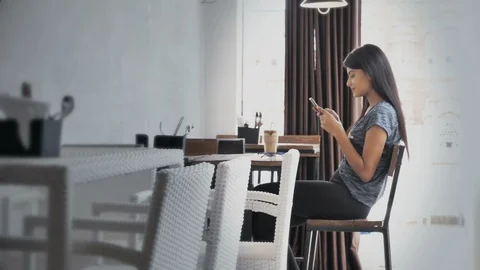 Lady checking cellphone in a modern cafe with a smile on her Video stock 94131976