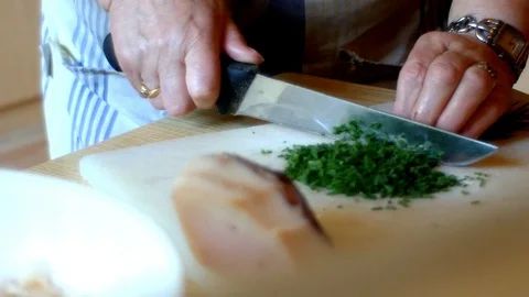 Lady chops chives for the preparation of Tyrolean dumplings Stock Footage 112652965