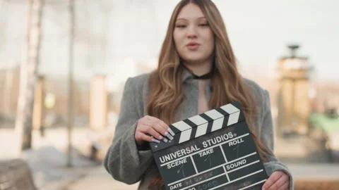 Lady with clapperboard in park setting. Outdoor shot of woman acting with camera Stock Footage 342431694
