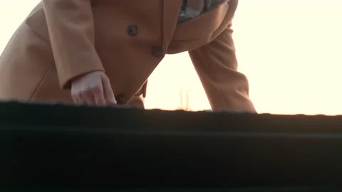 Lady in coat opens trunk of car and puts suitcase inside Stock Footage 167836271