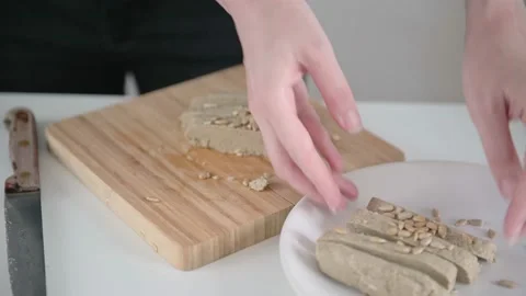 Lady cook serves halva slices taking from wooden board and putting white plate Stock Footage 157827843