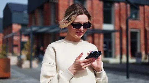 Lady in cool sunglasses using smartphone for entertainment while waiting for bus Video stock 274126344