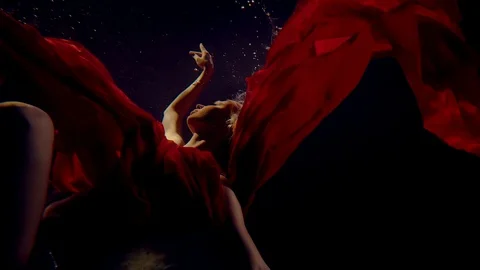 Lady is diving underwater in darkness, wrapped red silk fabric Stock-Footage 102837125
