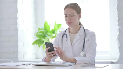 Lady Doctor using Smartphone While sitting in Clinic Stock Footage 205000716