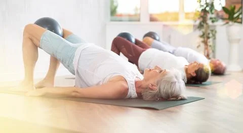 Lady does lightweight bridge pose - Setu Bandhasana and holds softball in lap. Stock Photos