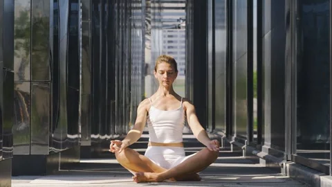 Lady does sun salutation meditating at urban park Video stock 272418103