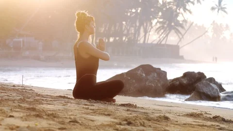 Lady does yoga on sandy beach near burning incense stick Stock Footage 109487830