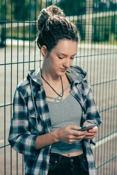 Lady with dreadlocks smiling while looking at the smartphone Stock Photos