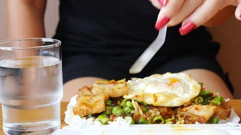 Lady eating  rice topped with fried crispy pork and basil with fried egg and Stock Footage 101005653