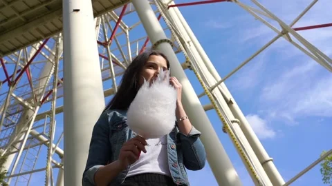 Lady eats cotton candy under amusement park attraction Stock Footage 131416028