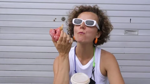 Lady eats snack donut with coffee. Close-up woman in white T-shirt and white Video stock 259151452