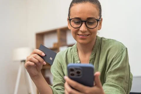 Lady effortlessly processes her credit card payment on her phone for an online Foto stock