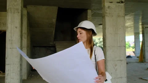 Lady engineer holds floor plan standing on construction site 스톡 동영상 317609568