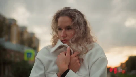 Lady feeling cold covering herself with white coat under cloudy urban sky Video stock 307775490