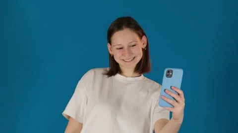 Lady finds better angle to take selfie on blue background Stock Footage 274293335