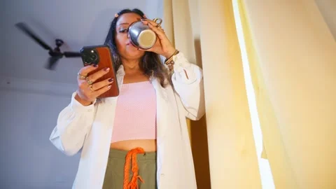 Lady finishes coffee while scrolling her device Stock Footage 307897625