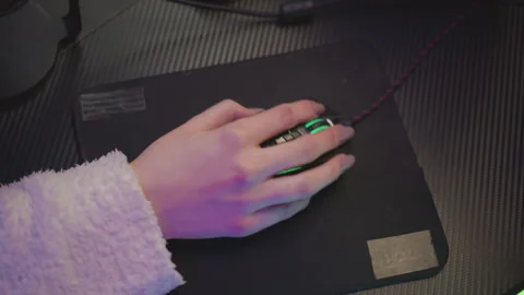 Lady in fluffy sweater using mouse with green light on desk setup Stock Footage 307458838