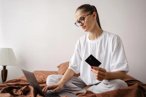 Lady in glasses using laptop computer. Woman making online transaction and sh Stock Photos
