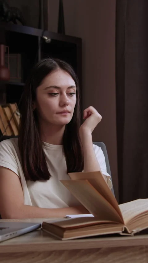 Lady graduate reflects on read assignment while preparing homework in library. Stock Footage 305409075