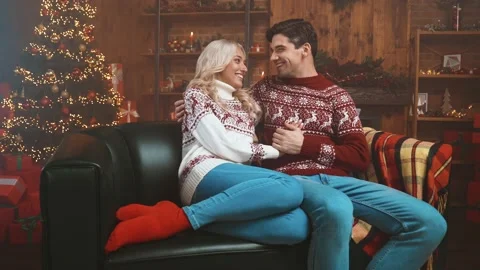 Lady guy sit cozy sofa cuddle newyear tree x mas print sweater lights indoors Stock Footage 167077557