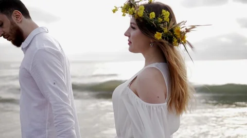 Lady with hair waved by wind walks with man along coastline Stock Footage 111750153