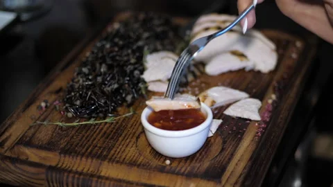 Lady hand holds silver fork and puts meat slice into sauce Stock Footage 140409061