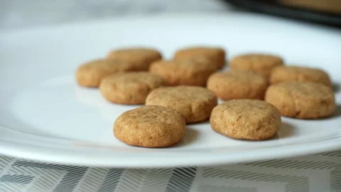 Lady hand puts small round cookies onto white ceramic plate Video stock 277319976