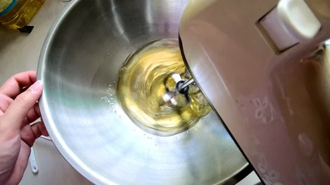 A lady Hands Mixing White Egg Cream In Bowl Using Motor Mixer Stock Footage 109406376