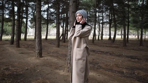 Lady in hat and long coat poses in pine forest slow motion Stock Footage 105293799