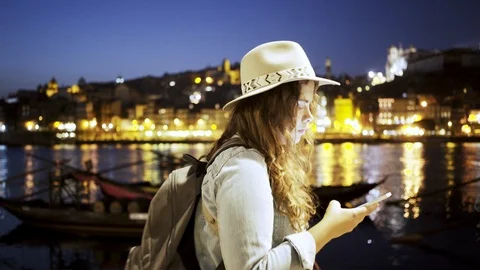 Lady in hat with backpack and smartphone on embankment Stock-Footage 99478349