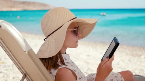 Lady in Hat Reads Electronic Book on E-Reader on Beach at Seaside in Summer Stock Footage 155409410