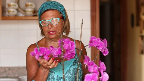 Lady with headband treats her orchids Stock Footage