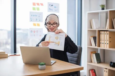 Lady in headset analysing data in charts on web conference Stock Photos